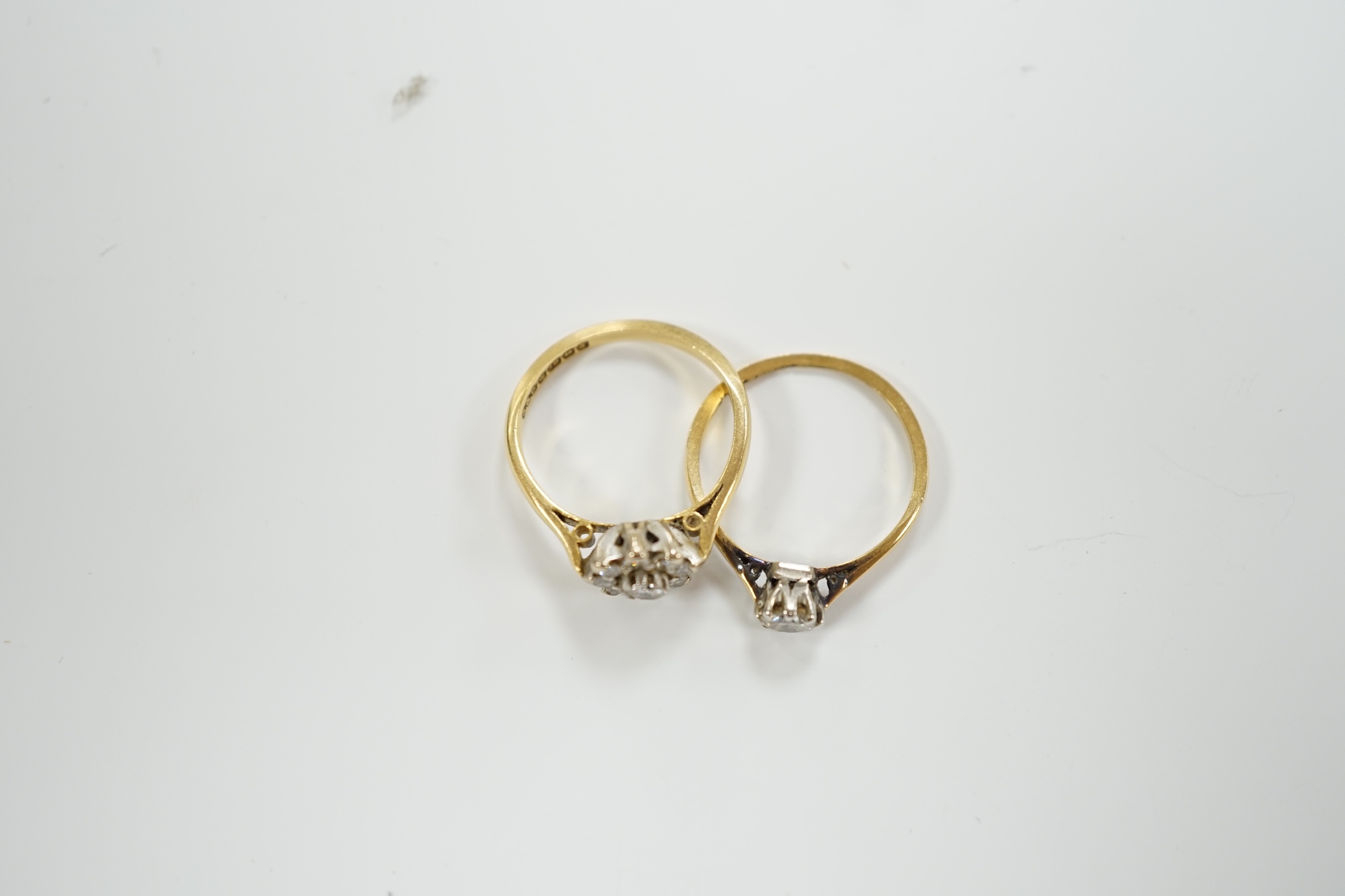 An 18ct gold and diamond cluster set flower head cluster ring, size K and an 18ct, plat. and solitaire diamond set ring, size L, gross weight 4.3 grams.